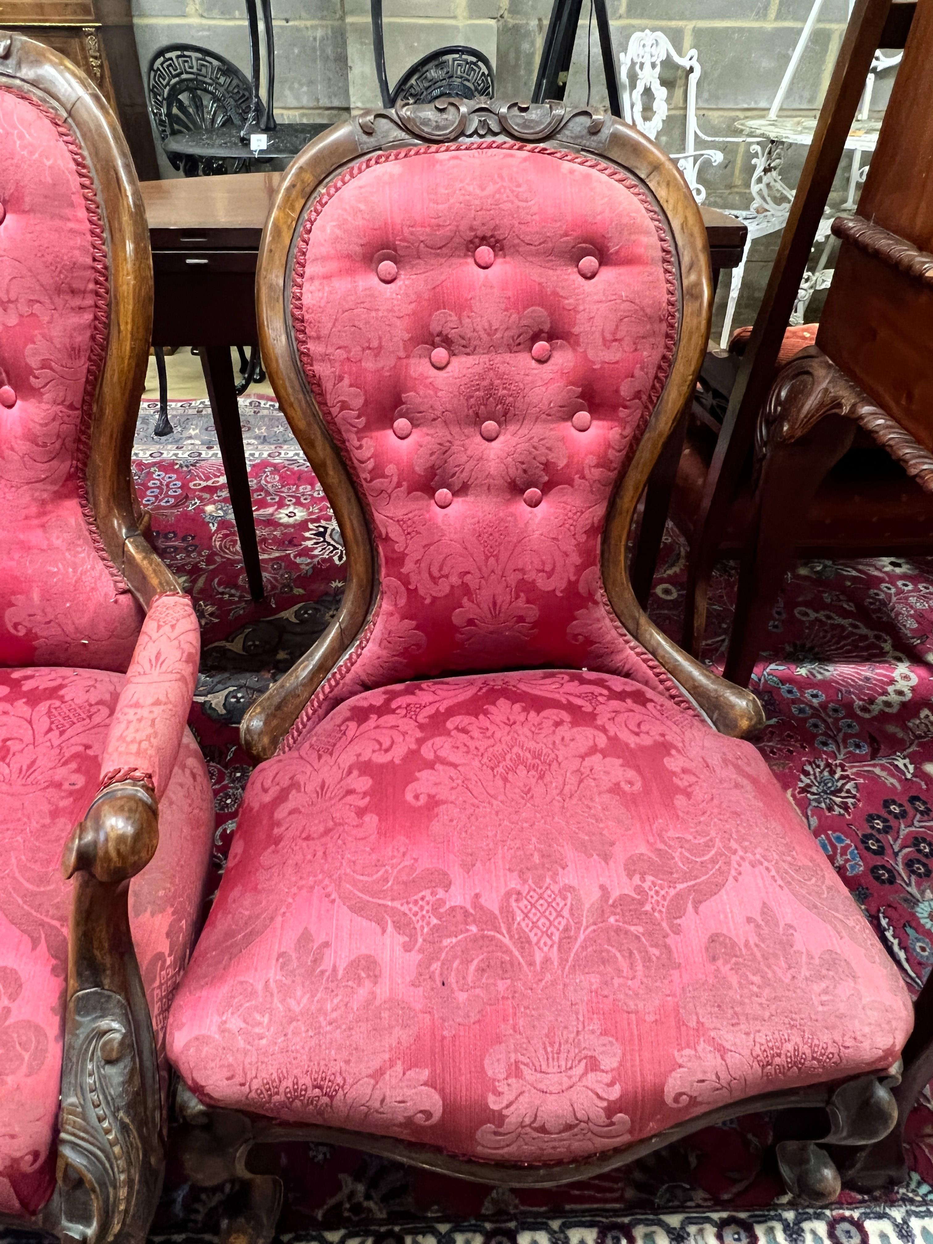 A pair of Victorian walnut spoon back upholstered chairs, one with arms